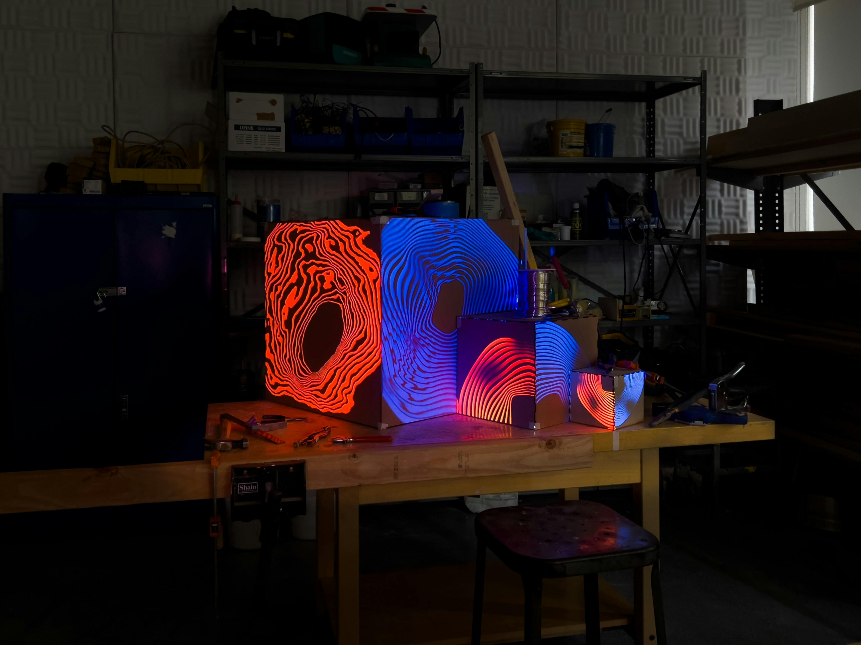 Projection mapping of a blue and orange pattern on the three cardboard cubes.