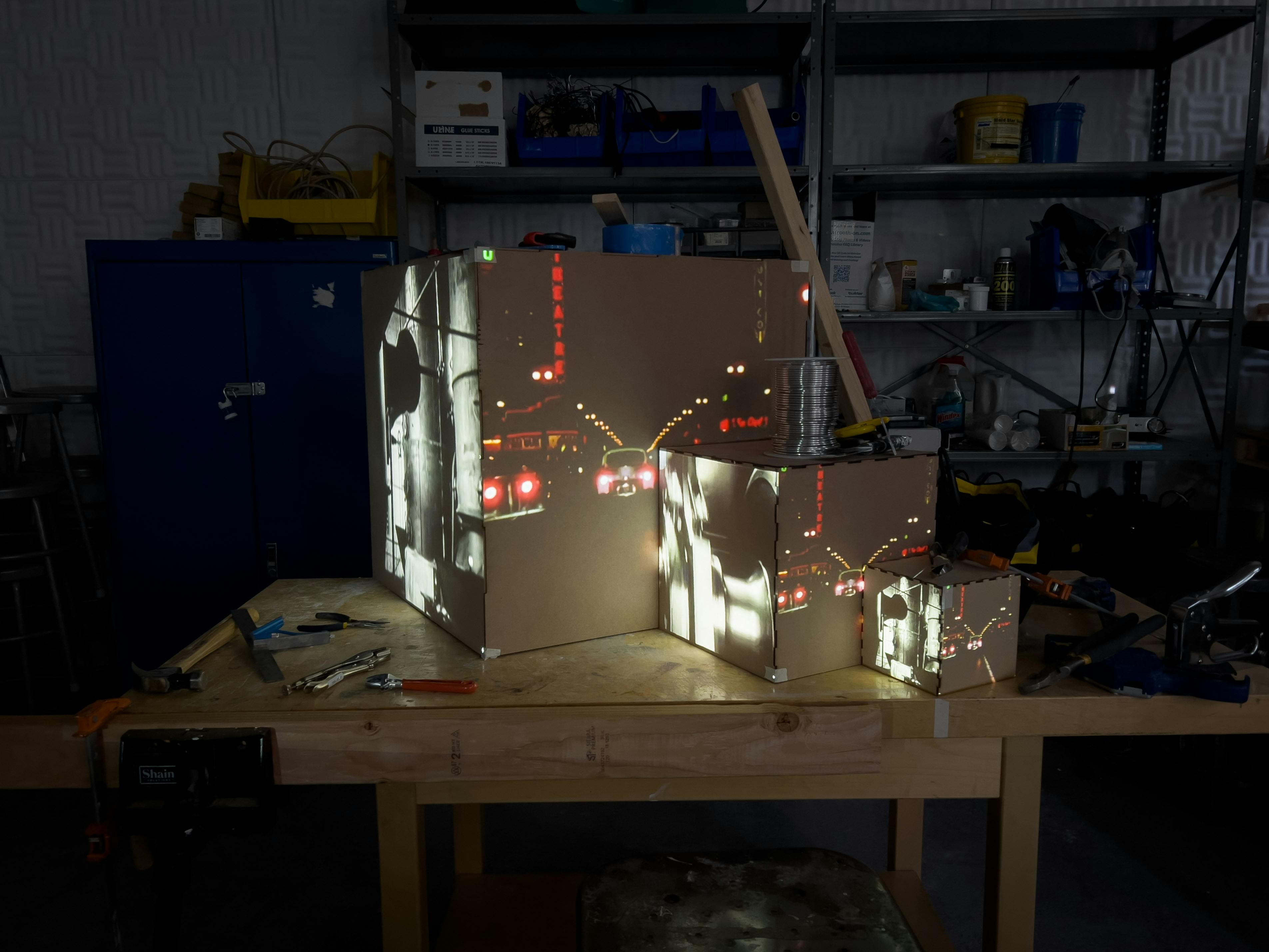 Video of a car driving at night projected onto the three cardboard cubes