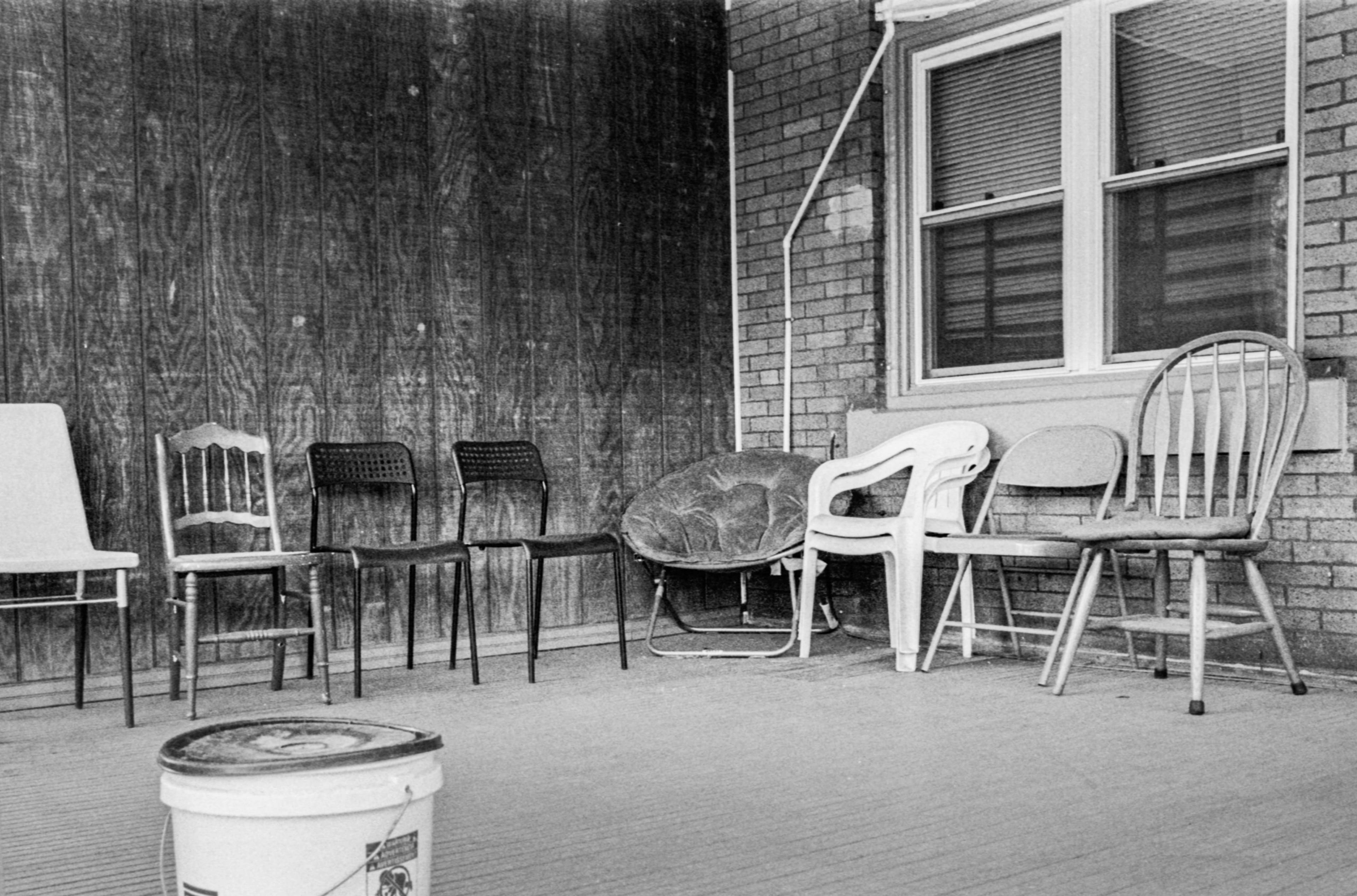 A porch with a collection of mismatched chairs.