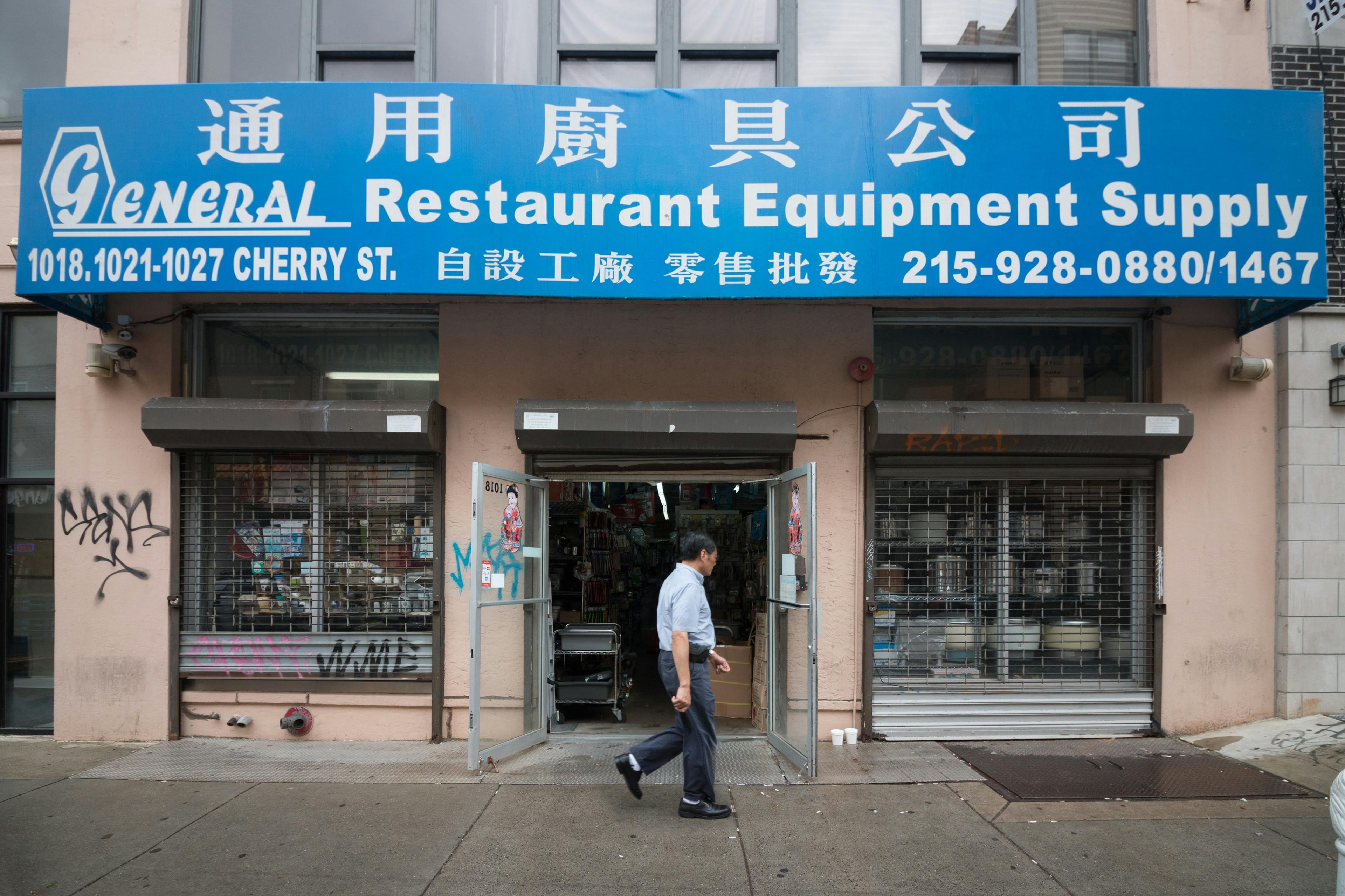 Man walking in front of a general store in Chinatown, Philadelphia.