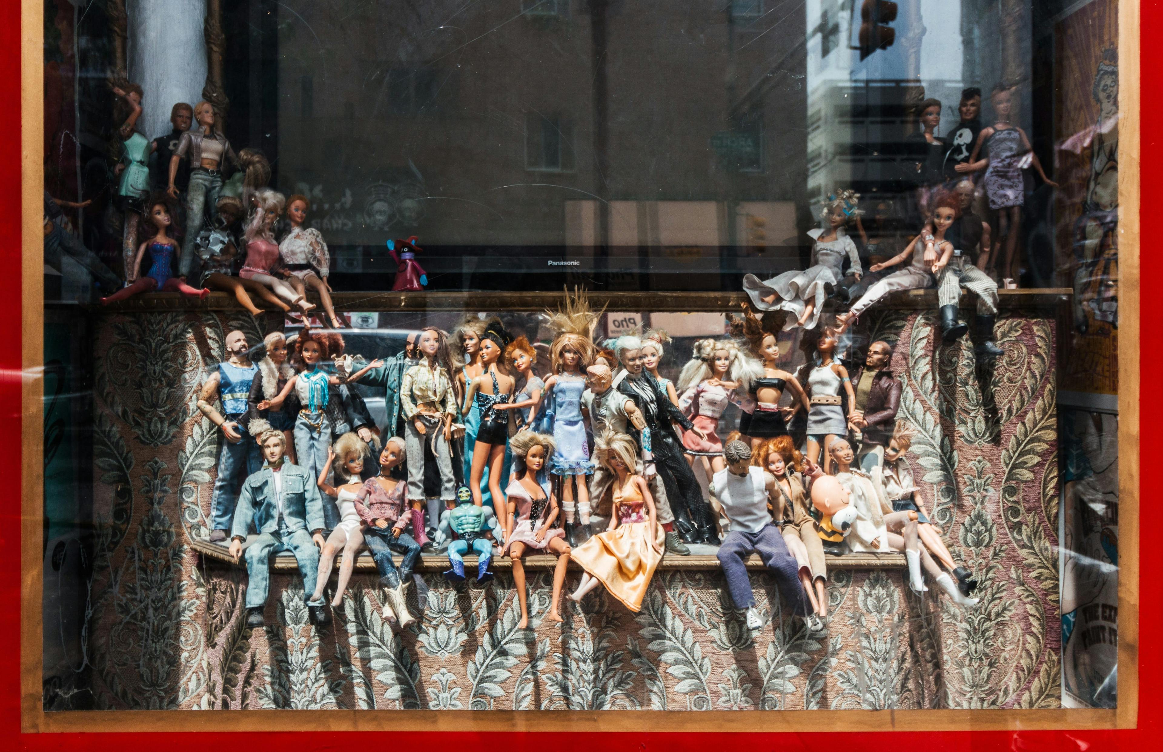An assortment of Barbie dolls in a window display.