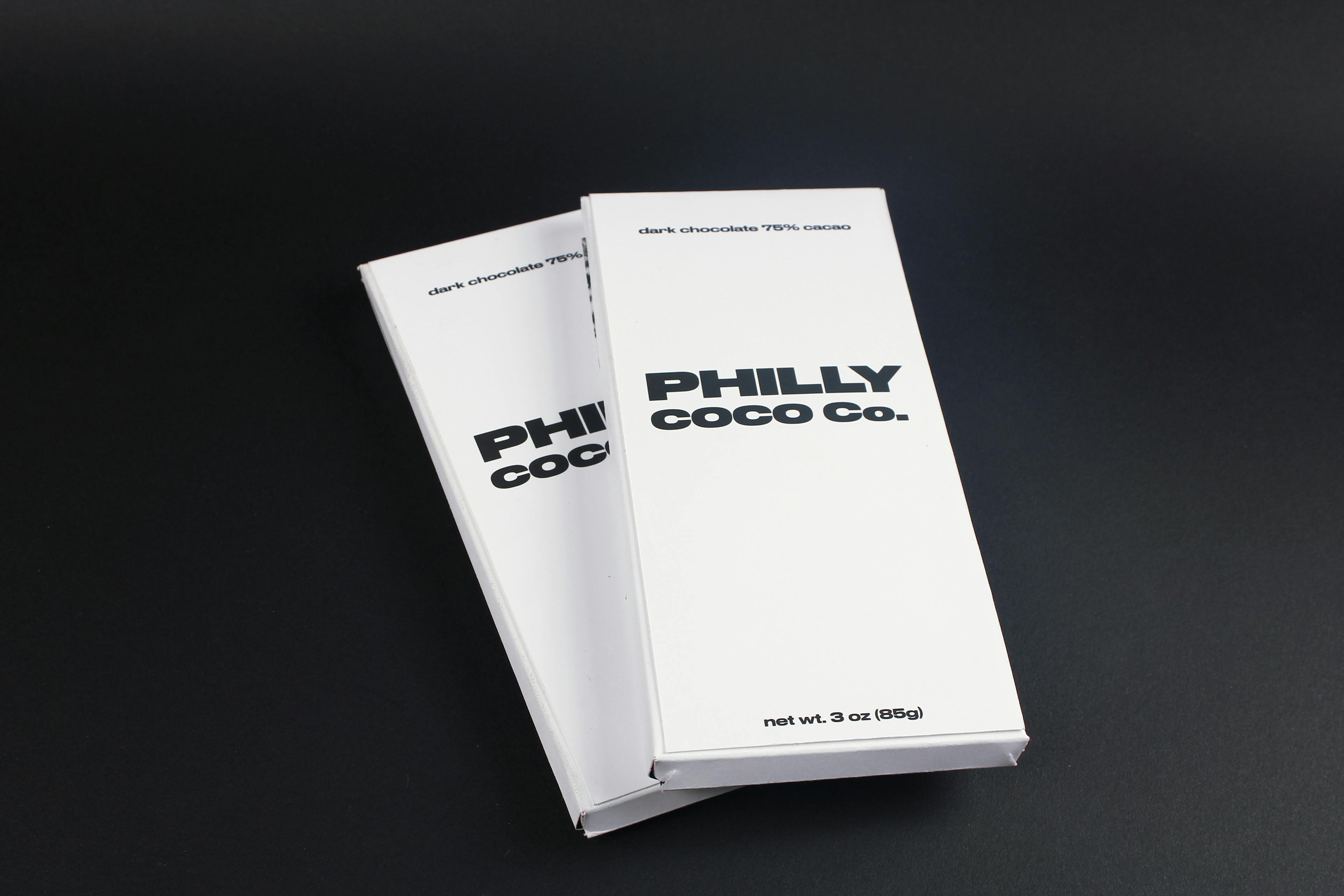 Two chocolate boxes with a white exterior with "PHILLY COCO Co." in bold dark text