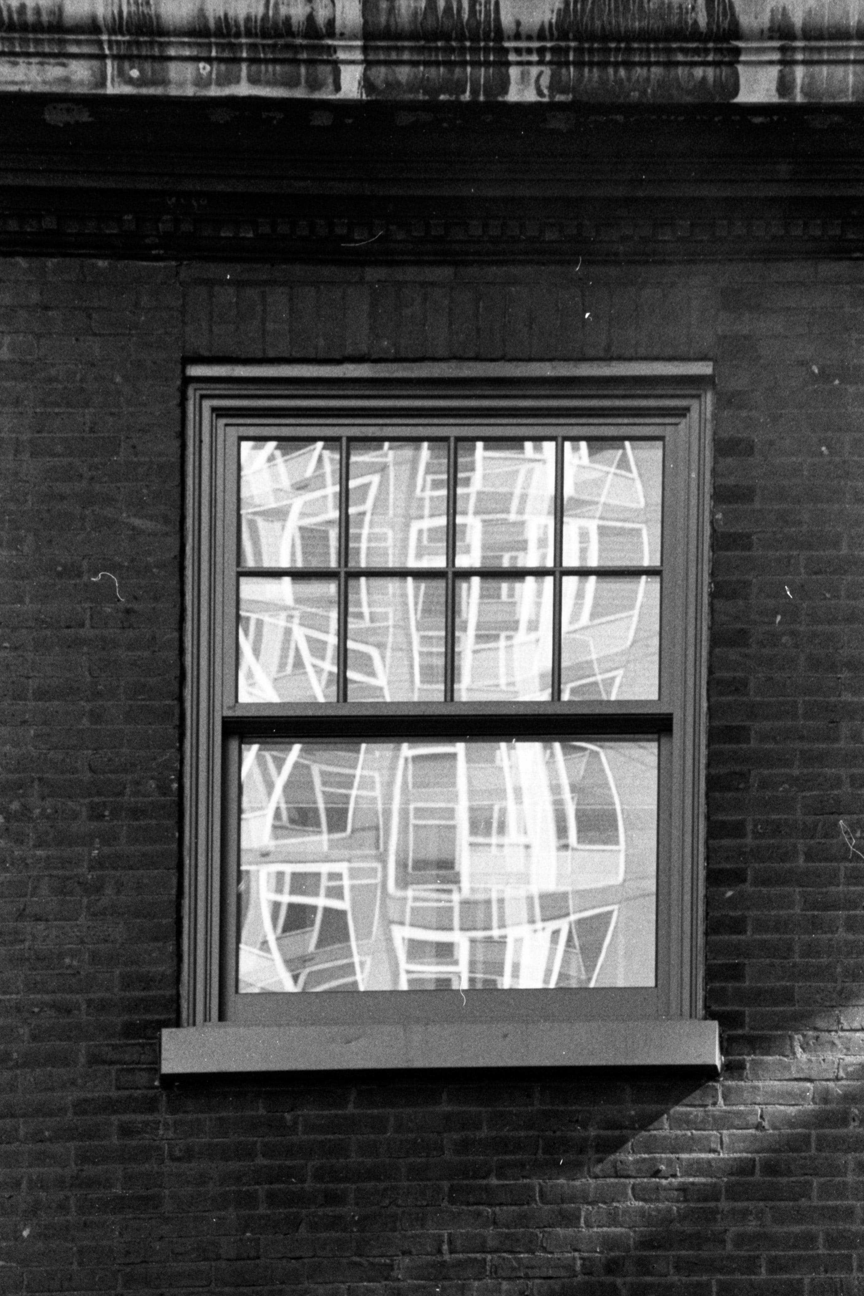 A window on a brick building with reflections of other windows.