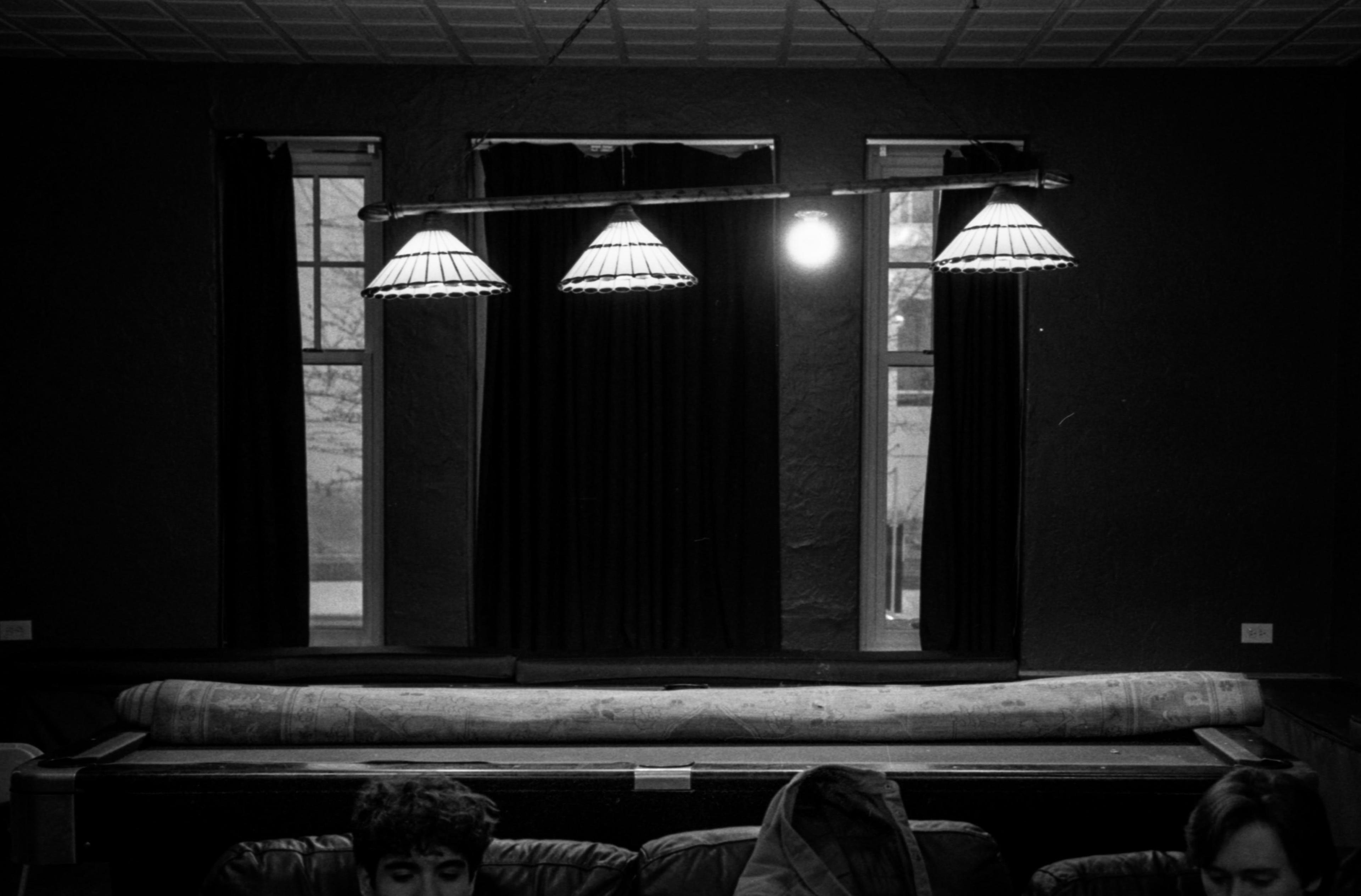 View of 4 lights hanging over a pool table with the middle right light without a cover